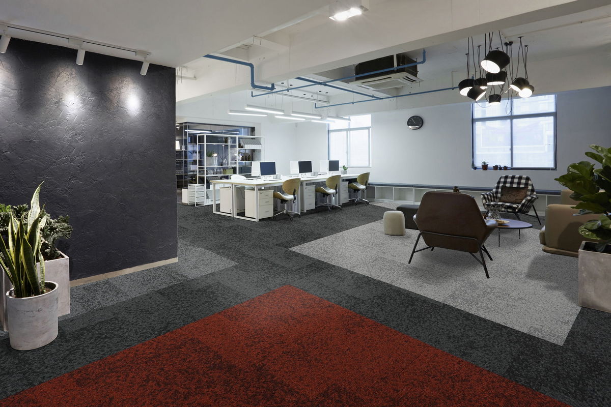 Patterned carpet tiles in grey and red zoning an open-plan office
